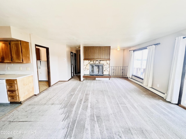 unfurnished living room with light carpet, a stone fireplace, and a baseboard heating unit