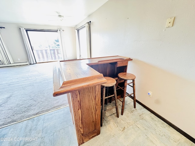 dining space featuring a baseboard heating unit, bar, and ceiling fan