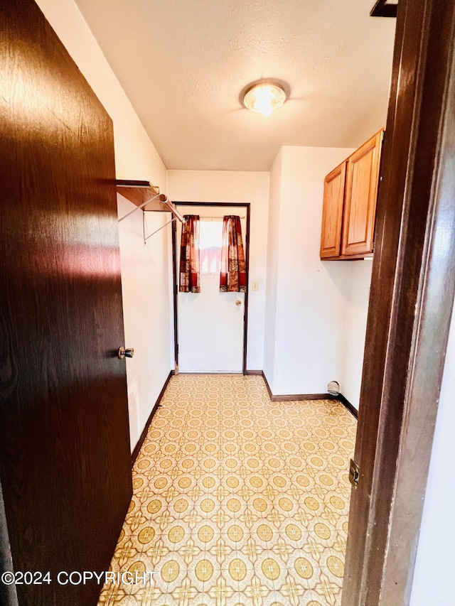 hallway featuring a textured ceiling and light tile flooring