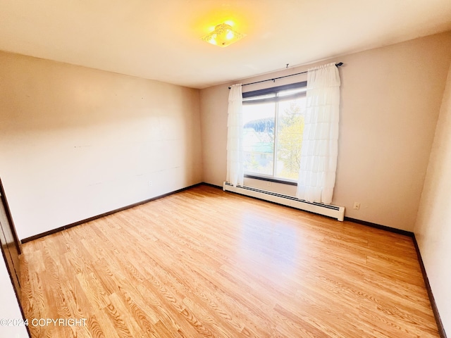 empty room with a baseboard heating unit and light hardwood / wood-style flooring