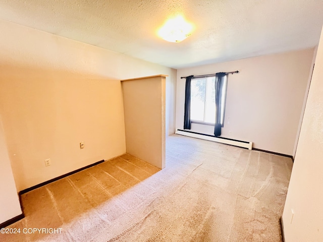 spare room featuring a baseboard heating unit, a textured ceiling, and carpet floors