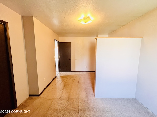 hallway with a textured ceiling and light colored carpet