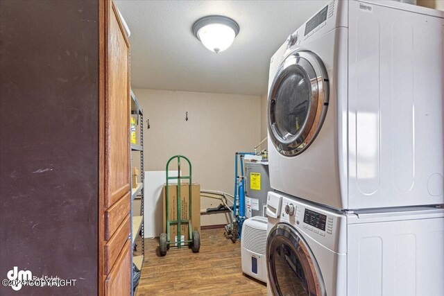 18226 Guernsey Rd, Wasilla, AK 99654 - clothes washing area featuring stacked washer and clothes dryer, wood finished floors, laundry area, and electric water heater
