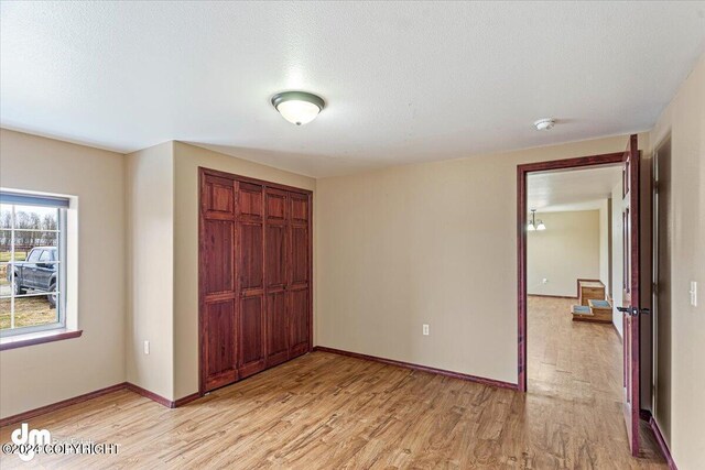 18226 Guernsey Rd, Wasilla, AK 99654 - unfurnished bedroom featuring a closet, a textured ceiling, baseboards, and light wood-type flooring