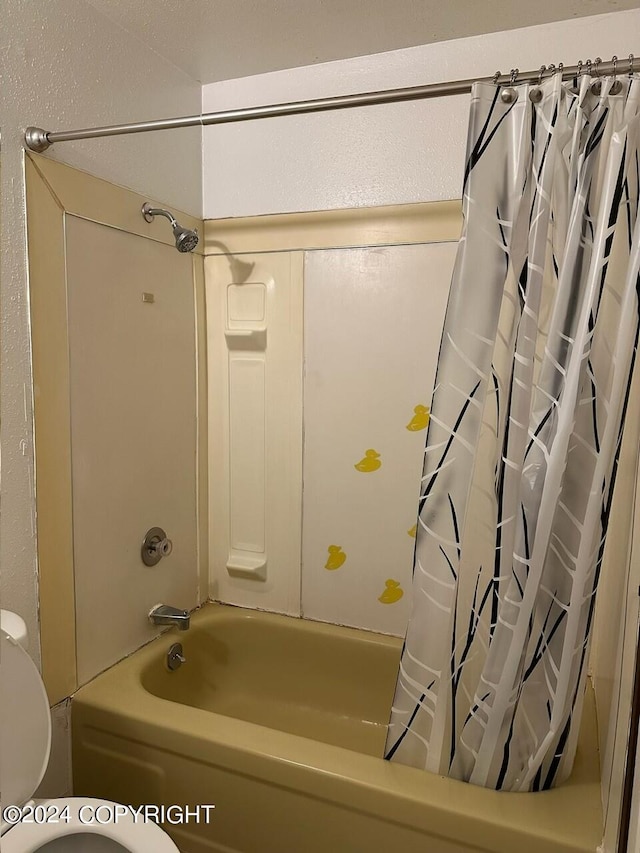 bathroom with toilet and shower / bath combo with shower curtain