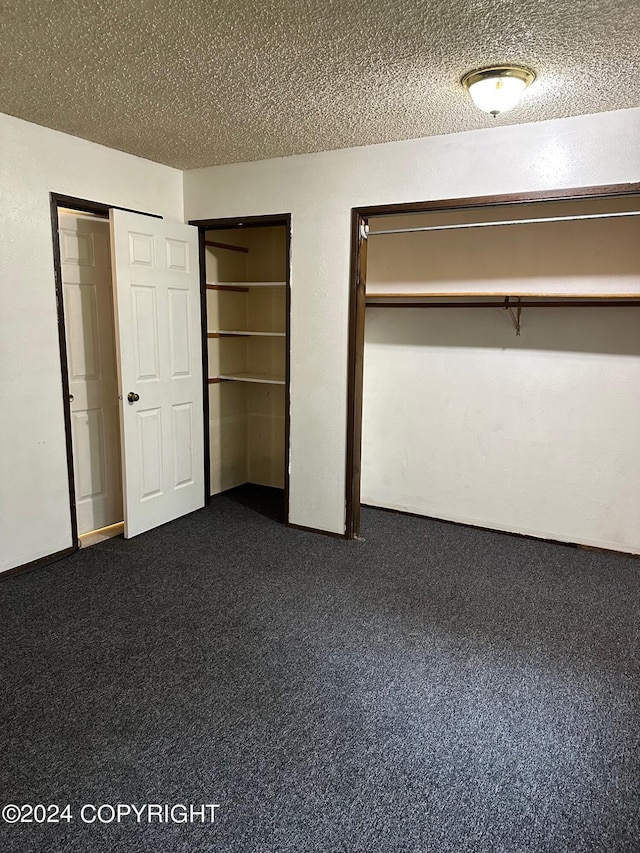 unfurnished bedroom with dark carpet and a textured ceiling