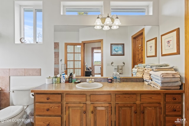 bathroom featuring vanity, an inviting chandelier, and toilet