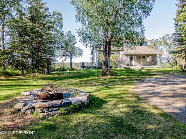 view of yard featuring a porch and a fire pit