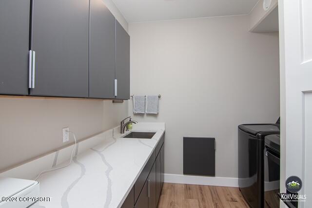 washroom featuring washer and dryer, sink, light hardwood / wood-style floors, and cabinets