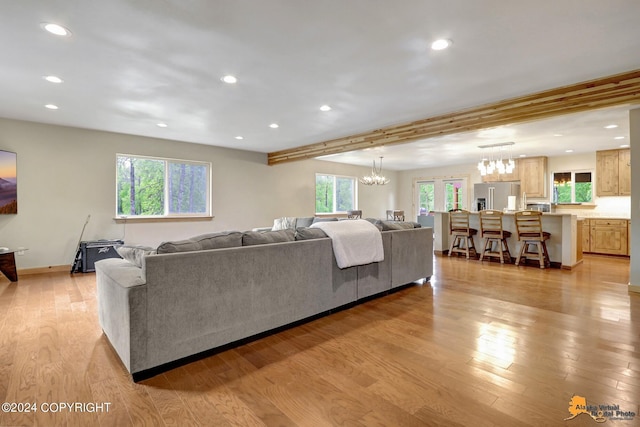 living room featuring a notable chandelier, light hardwood / wood-style flooring, and beamed ceiling