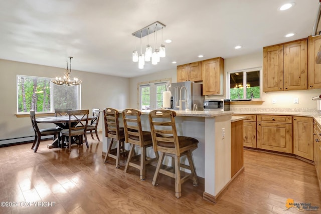 kitchen featuring an island with sink, appliances with stainless steel finishes, a breakfast bar, and decorative light fixtures