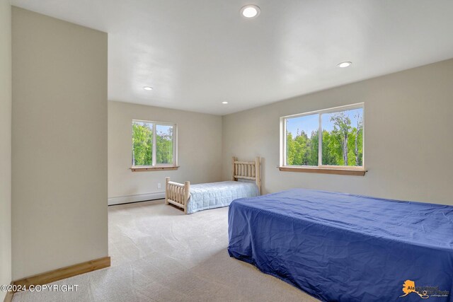 bedroom featuring light carpet and a baseboard heating unit