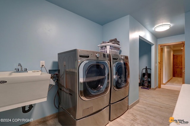 laundry room featuring washer and dryer, sink, and light hardwood / wood-style floors