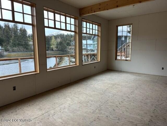 unfurnished room with beam ceiling