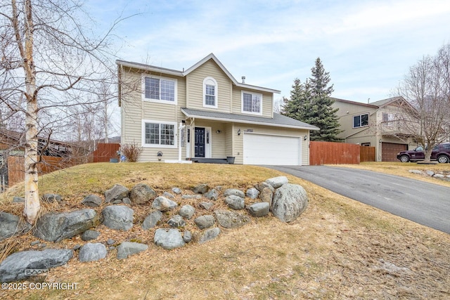 traditional-style home featuring aphalt driveway, fence, and a garage