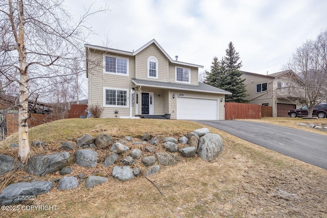 traditional-style house with aphalt driveway, an attached garage, and fence