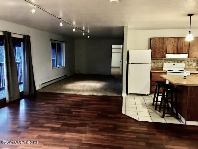 kitchen featuring white appliances, extractor fan, baseboard heating, wood-type flooring, and a breakfast bar area