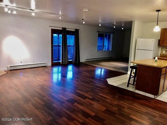 interior space with hardwood / wood-style floors, track lighting, and a baseboard radiator