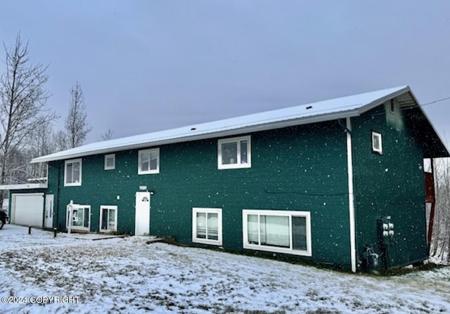 snow covered rear of property with a garage