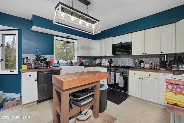 kitchen featuring white cabinetry, decorative light fixtures, butcher block counters, and black appliances