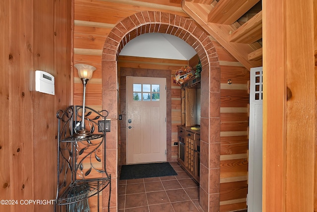 entryway featuring dark tile patterned floors and wooden walls