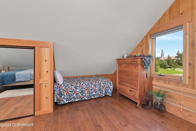 bedroom with hardwood / wood-style flooring, lofted ceiling, and wood walls