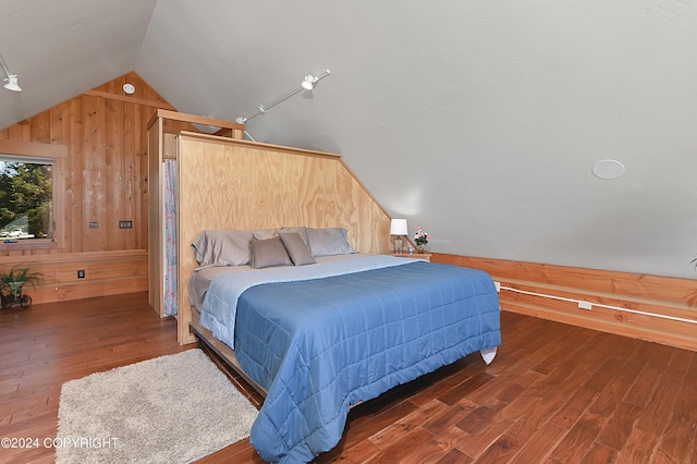 bedroom with wooden walls, dark hardwood / wood-style flooring, and vaulted ceiling