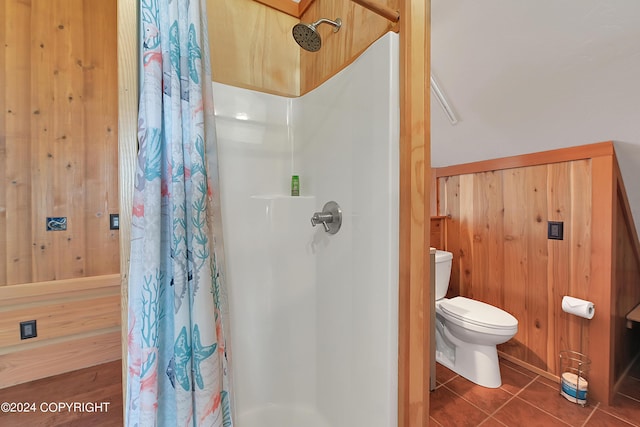 bathroom with tile patterned flooring, toilet, curtained shower, and wooden walls