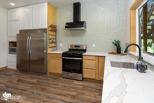 kitchen with wall chimney exhaust hood, stainless steel appliances, sink, white cabinetry, and plenty of natural light