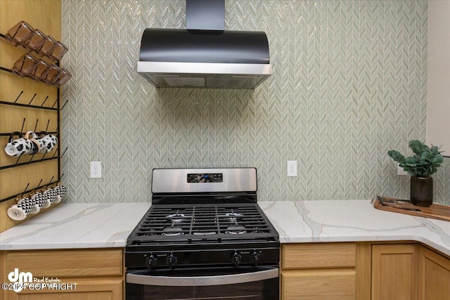 kitchen featuring light stone counters, wall chimney range hood, tasteful backsplash, and gas range