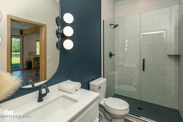 bathroom featuring vanity, a shower with shower door, and toilet