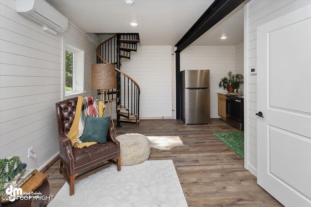 sitting room with beam ceiling, hardwood / wood-style flooring, a wall mounted AC, and wooden walls