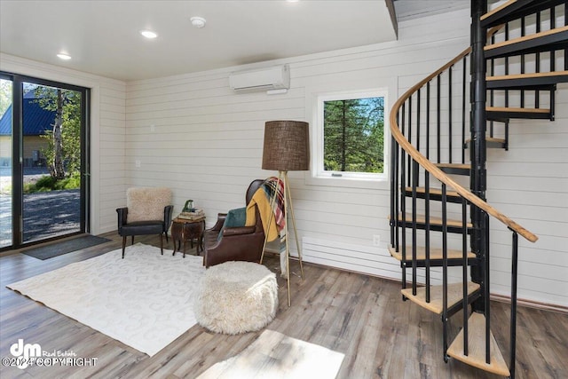 living area with a wall unit AC, wood walls, and wood-type flooring