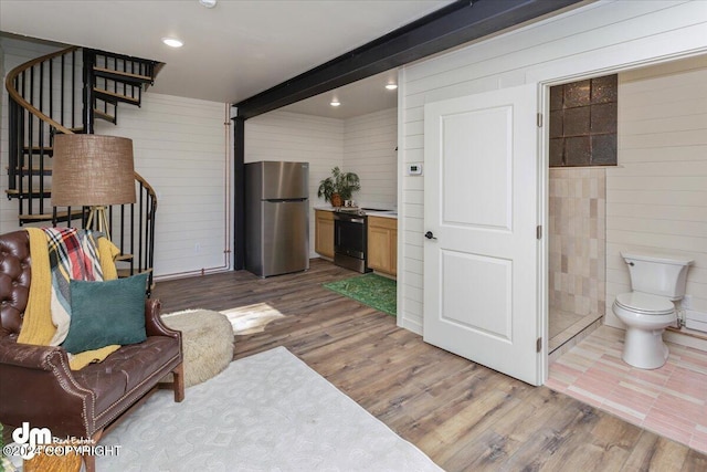 living area with wood walls, wood-type flooring, and beam ceiling