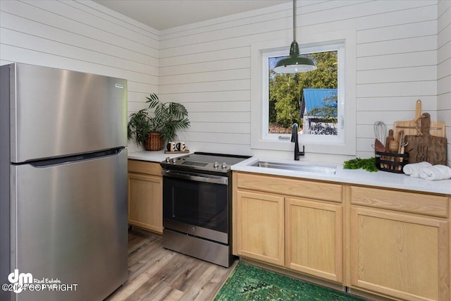 kitchen featuring wooden walls, light brown cabinets, sink, and appliances with stainless steel finishes