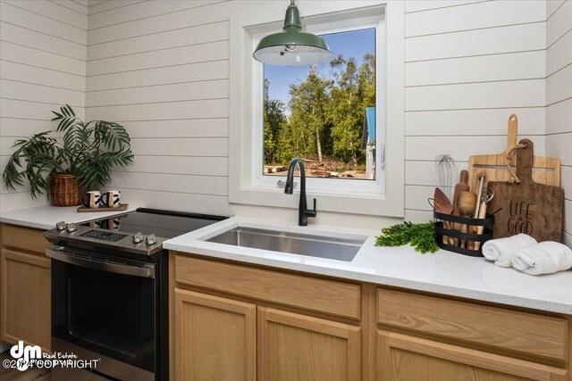 kitchen featuring electric range, pendant lighting, sink, and wooden walls