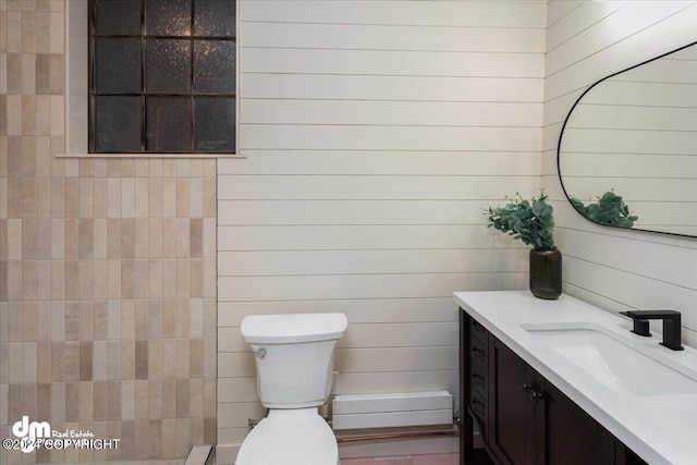 bathroom featuring wood walls, vanity, and toilet