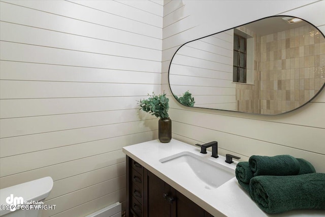 bathroom featuring vanity, toilet, and wooden walls