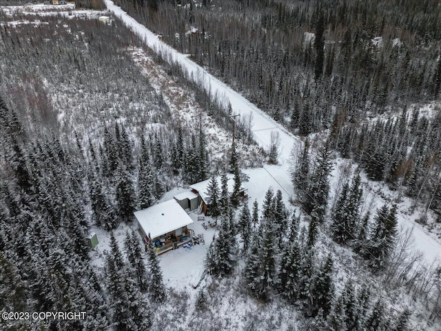 snowy aerial view featuring a wooded view