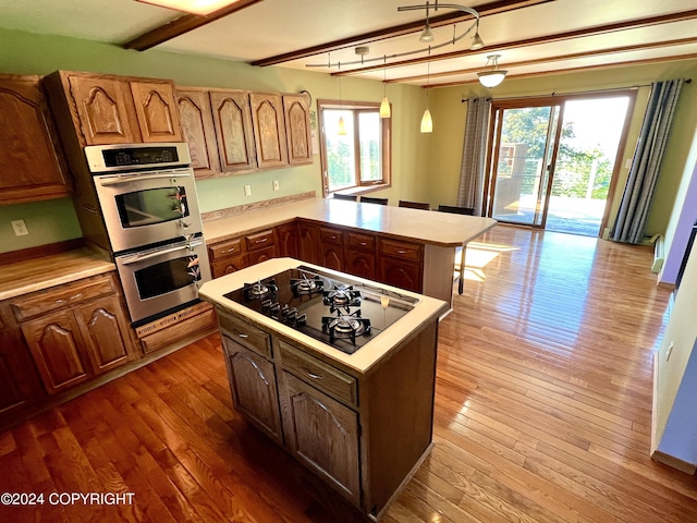 17041 Jacqueline Cir, Anchorage, AK 99516 - kitchen with black cooktop, double oven, light countertops, hardwood / wood-style flooring, and beam ceiling
