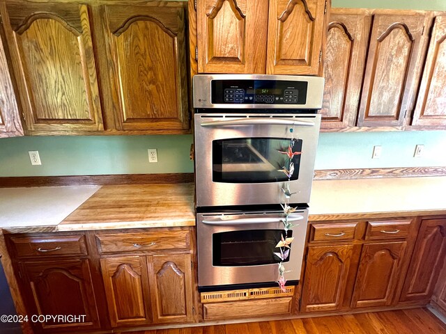 17041 Jacqueline Cir, Anchorage, AK 99516 - kitchen with double oven, light countertops, brown cabinetry, and light wood-style floors