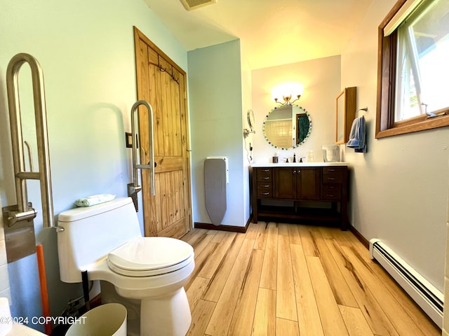 17041 Jacqueline Cir, Anchorage, AK 99516 - bathroom with a baseboard radiator, toilet, wood finished floors, vanity, and baseboards