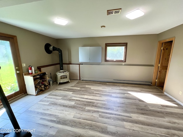 17041 Jacqueline Cir, Anchorage, AK 99516 - spare room with plenty of natural light, baseboard heating, a wood stove, and light wood finished floors