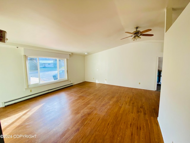 empty room featuring a baseboard heating unit, ceiling fan, hardwood / wood-style floors, and vaulted ceiling