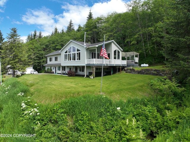 rear view of property featuring a wooden deck and a lawn