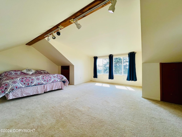 carpeted bedroom featuring rail lighting and vaulted ceiling with beams