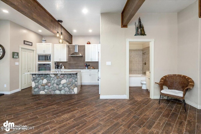 kitchen featuring white cabinetry, wall chimney range hood, decorative light fixtures, and appliances with stainless steel finishes