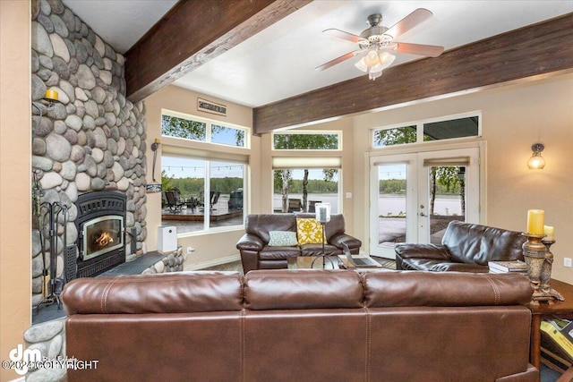 living room featuring beamed ceiling, a stone fireplace, ceiling fan, and french doors