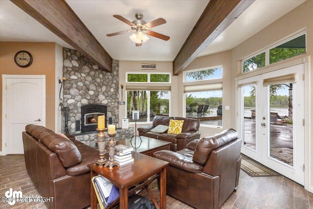 living room featuring a stone fireplace, plenty of natural light, hardwood / wood-style floors, and beam ceiling