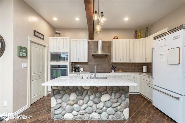 kitchen with light stone counters, a center island with sink, wall chimney exhaust hood, and appliances with stainless steel finishes